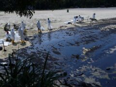 Workers clean oil spill along Sentosa’s Tanjong Beach area in Singapore (Suhaimi Abdullah/AP)