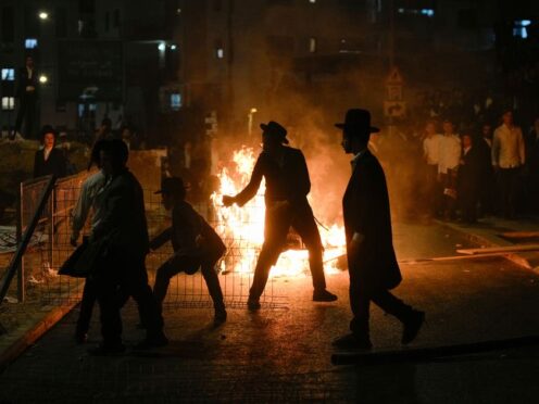 Ultra-Orthodox Jewish men burn rubbish during the protest (Ohad Zwigenberg/AP)