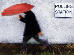 A man makes his way to a polling station in the rain (David Cheskin/PA)