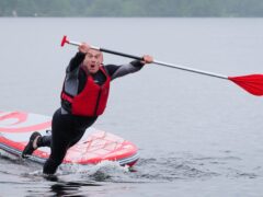 Liberal Democrat leader Sir Ed Davey topples off a paddleboard into Windermere, in the Lake District, one of several stunts he took part in on the campaign trail (Peter Byrne/PA)