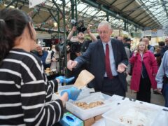 Northern Ireland Secretary Hilary Benn buys cookies during a visit to St George’s Market in Belfast, following the Labour Party’s victory in the 2024 General Election (Niall Carson/PA)