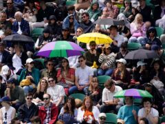Spectators sheltered from the rain as awaited the start of play on day seven of Wimbledon (Jordan Pettitt/PA)