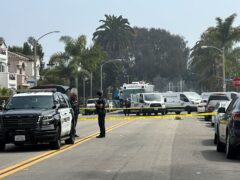 Police officers stand guard at the crime scene where police say two people were killed and three others injured in Huntington Beach, California (Eugene Garcia/AP)