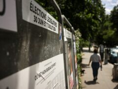 A woman walks past campaign boards for the parliamentary elections (Thomas Padilla/AP)