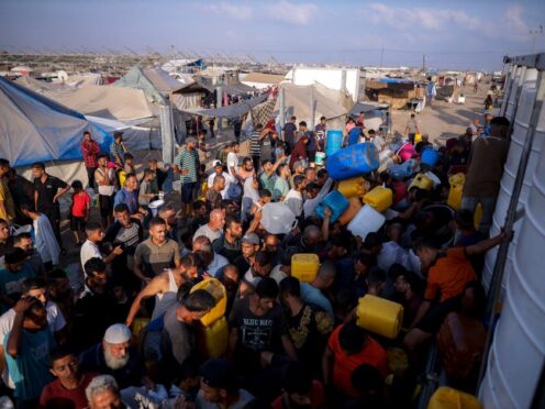 Palestinians displaced by the Israeli bombardment of the Gaza Strip queue for water at a makeshift tent camp in the southern town of Khan Younis on Monday (Jehad Alshrafi/AP)