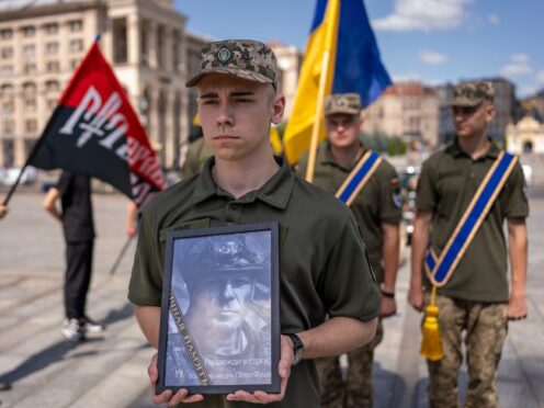 A Ukrainian serviceman carries a portrait of British combat medic, volunteer, Peter Fouche (AP Photo/Alex Babenko)
