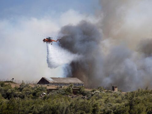 A firefighting helicopter drops water near Athens (Yorgos Karahalis/AP)