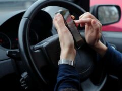 It is illegal for a hand-held device to be used for most actions while a vehicle is stopped at traffic lights or queuing in traffic (Alamy/PA)
