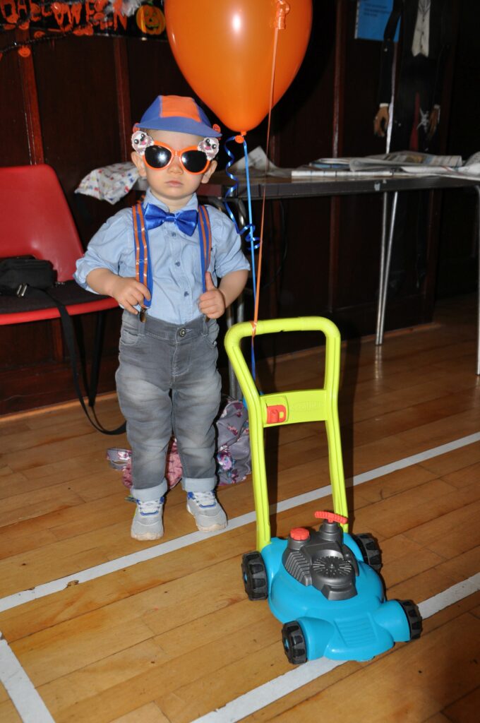 Dressed as Mr Blippi, a young boy poses for the camera.