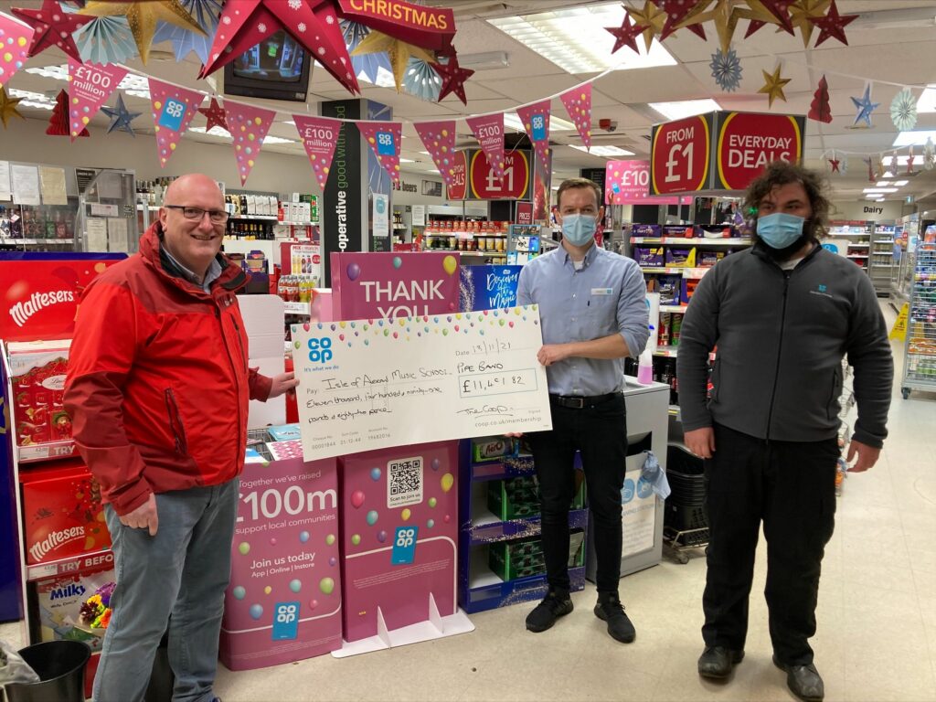 Andrew Dickie from the Isle of Arran Music School receives the cheque from Invercloy Co-op manager Stuart Godfrey and member pioneer Scott Harwood.