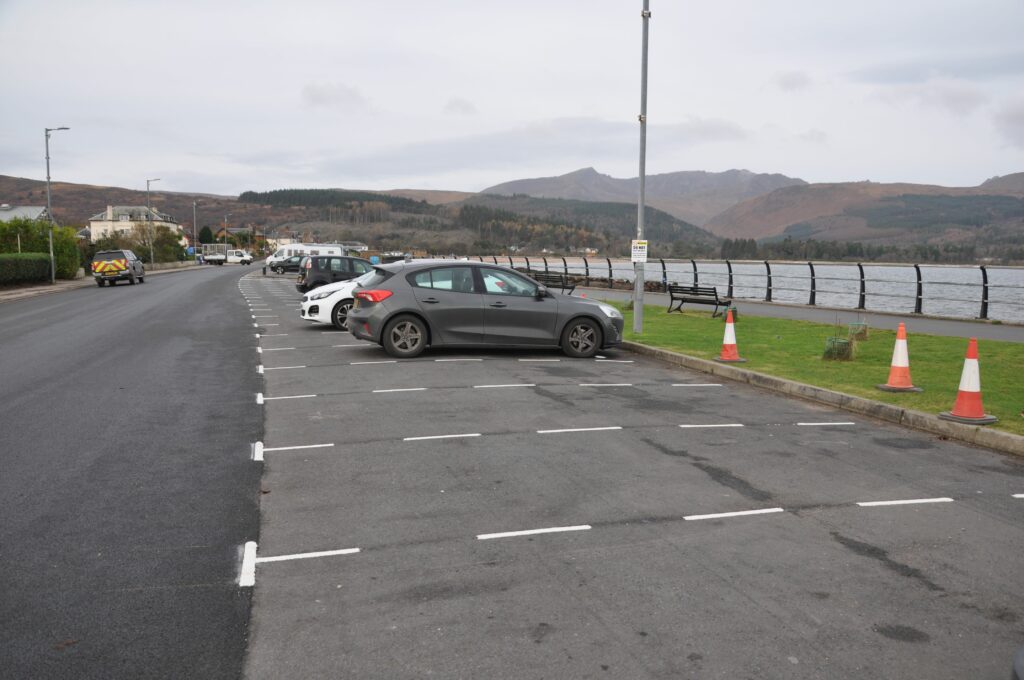 Demarcated parking lines extend from the ferry terminal to the end of the parking allocation near the Book and Card shop.