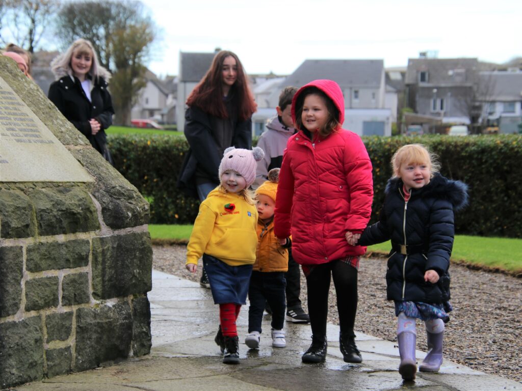 Emelie, sporting a yellow hoodie donated by Kintyre Hire along with £250 sponsorship, beams as she completes a lap of the war memorial with her friends.