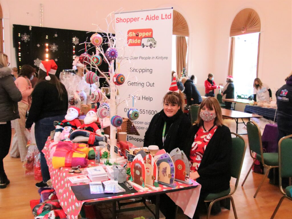 Michele Strang and Morag McMillan selling goods from the Shopper-Aide stall.