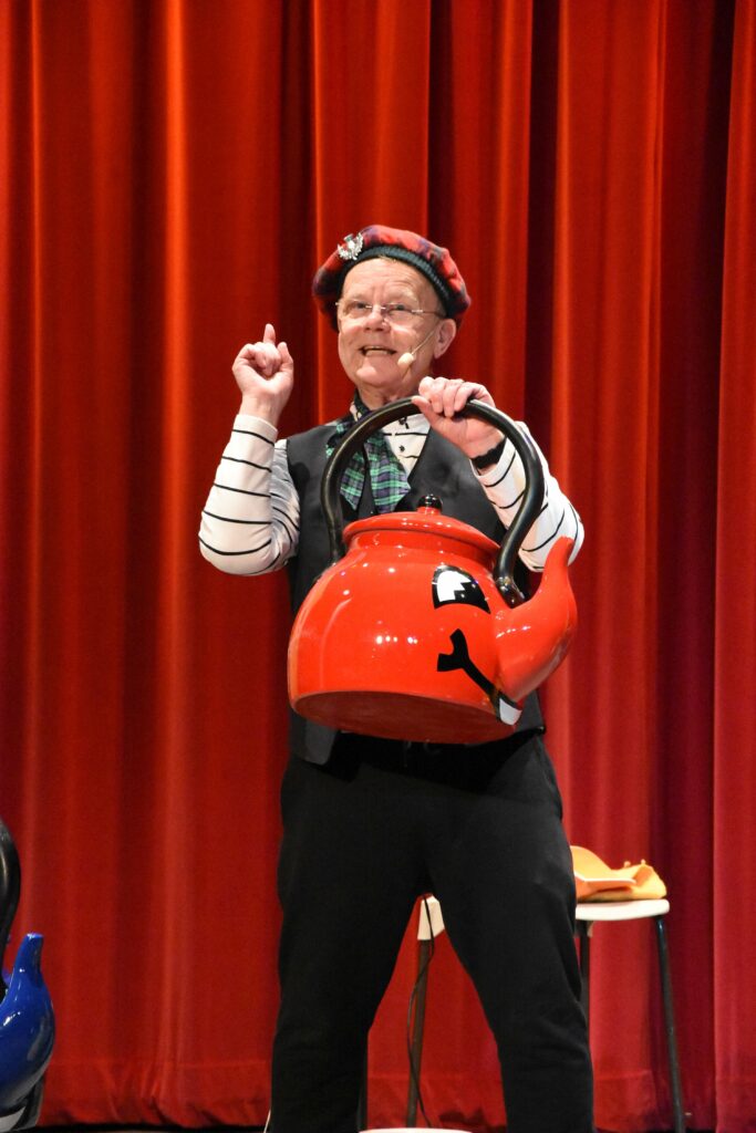 Artie has a look inside one of his singing kettles while the audience belt out 'Spout, handle, lid of metal, what's inside the singing kettle?’