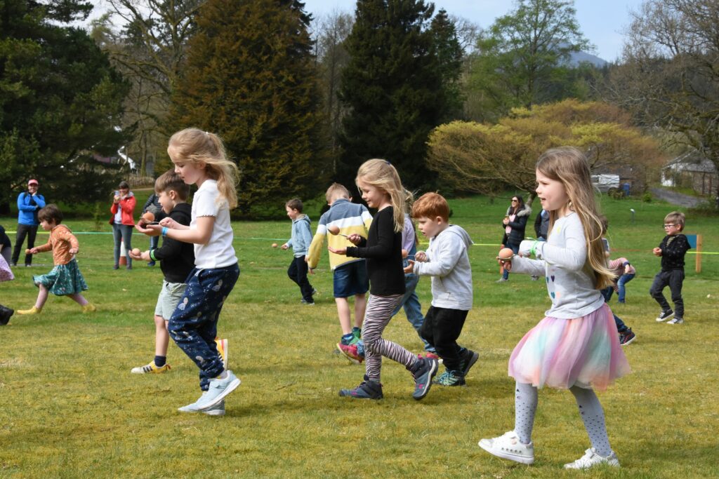 Children in the under six egg and spoon race concentrate on protecting their eggs.