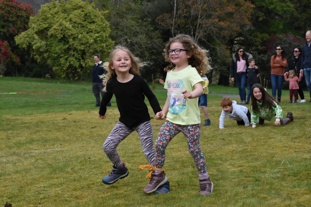 Two young girls share a laugh in the three-legged race.