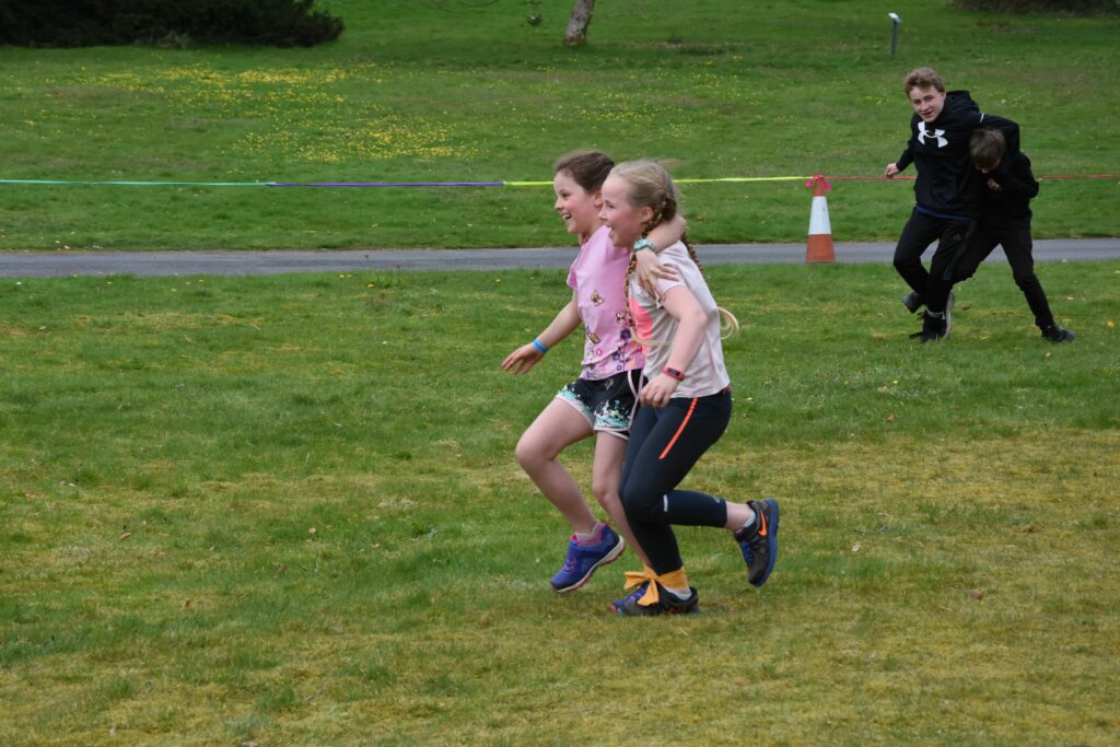 Winners by a mile, two young girls run in unison to win the three-legged race.