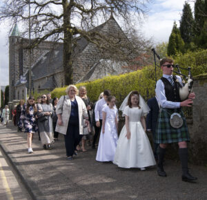 Piper Ronnie McIntosh leads the procession from St. Mary's Church to marched from the church to the celebration lunch in the Alexandra Hotel. Photograph: Iain Ferguson, alba.photos NO F17 St Columbas 1st Communion 02
