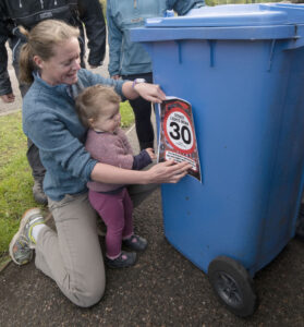  Joanne Mackin and her daughter Isabelle badge up their bin to highlight the speed limit to passing motorists. Photograph: Iain Ferguson, alba.photos NO F20 Corpach speed limit 05