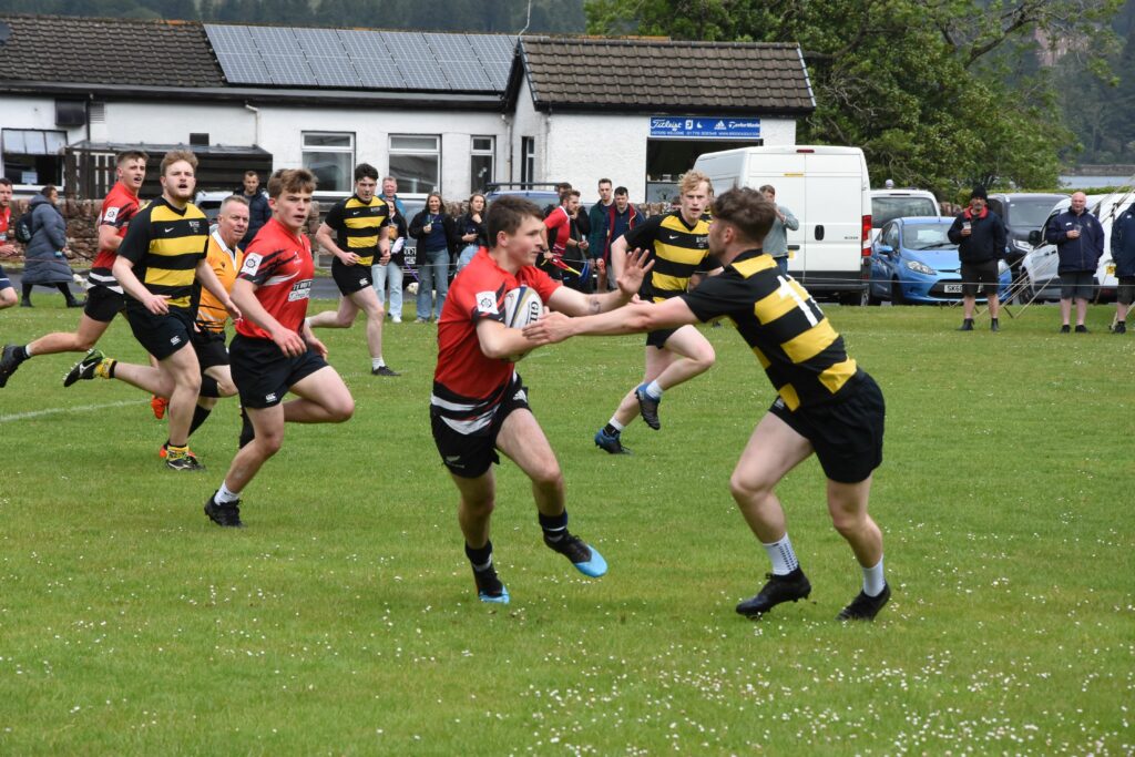 Arran player, Rory Currie deflects a tackle by a Southern Kites player.
