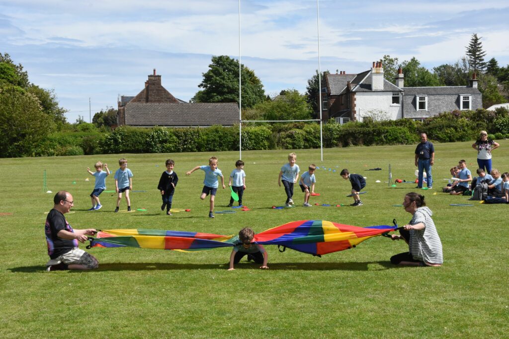 A pupil emerges from under a colourful tarp during an obstacle course race.