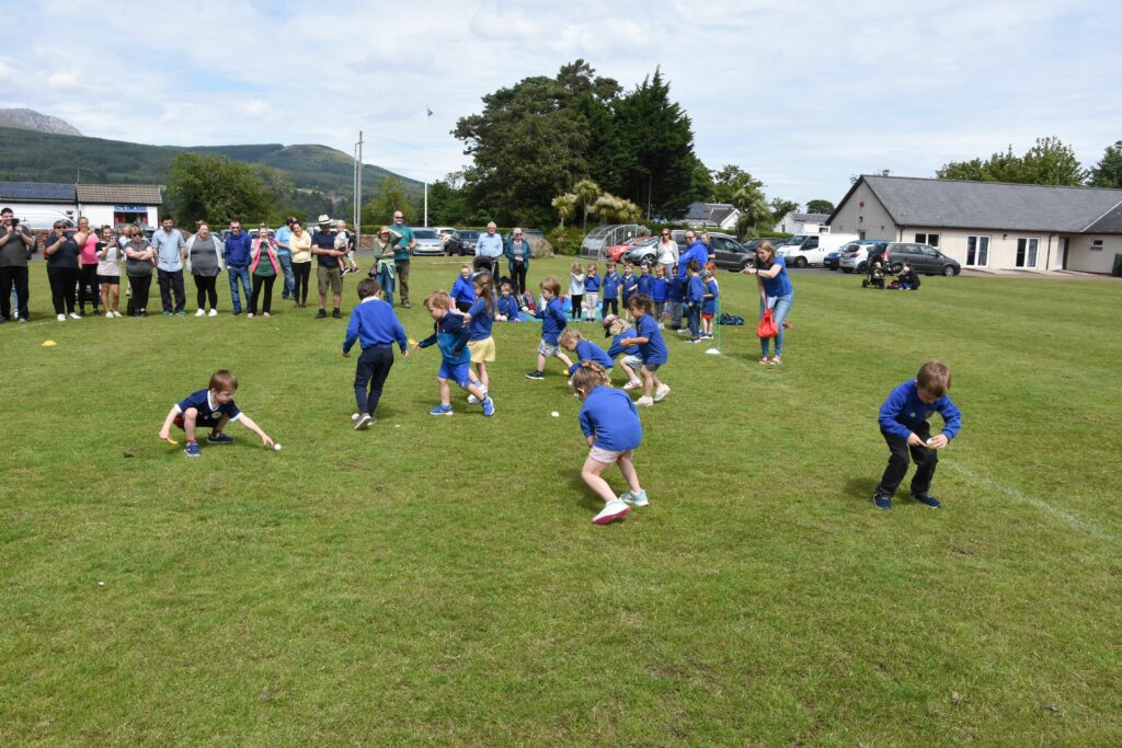 Early Years pupils scramble to pick up their eggs near the start line.