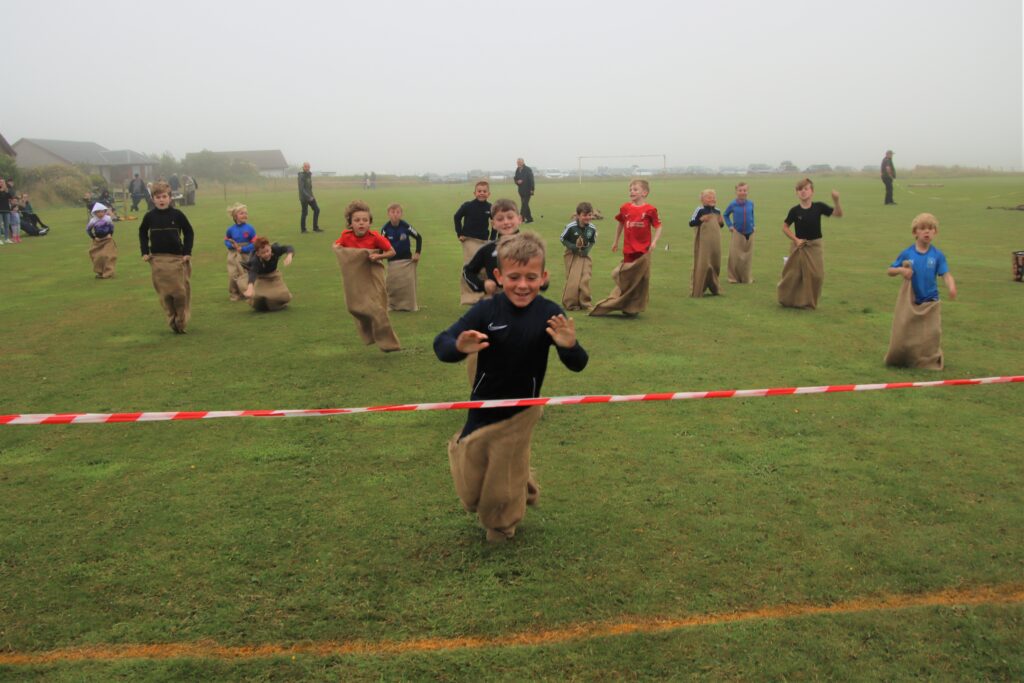 Leaping over the finish line in the sack race.