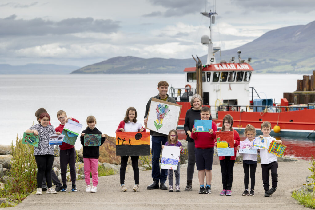 Jonathan Walker and Rhona Taylor with the primary children and their paintings beside the pier in Carradale. Photograph: Martin Shields.