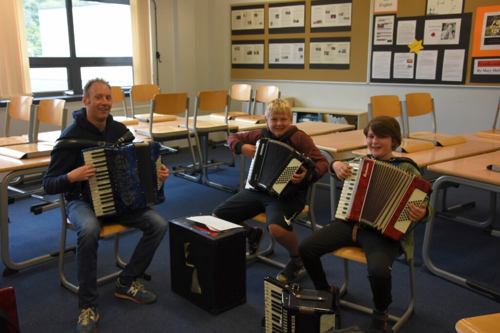 John Somerville teaches two enthusiastic pupils the accordion.