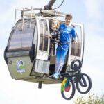 Mikayla Parton and Reece Wilson display the 2023 UCI Cycling World Championships 'Squiggly Bike' logo from a gondola at Nevis Range. Photograph: Phunkt NO F21 - cycling worlds