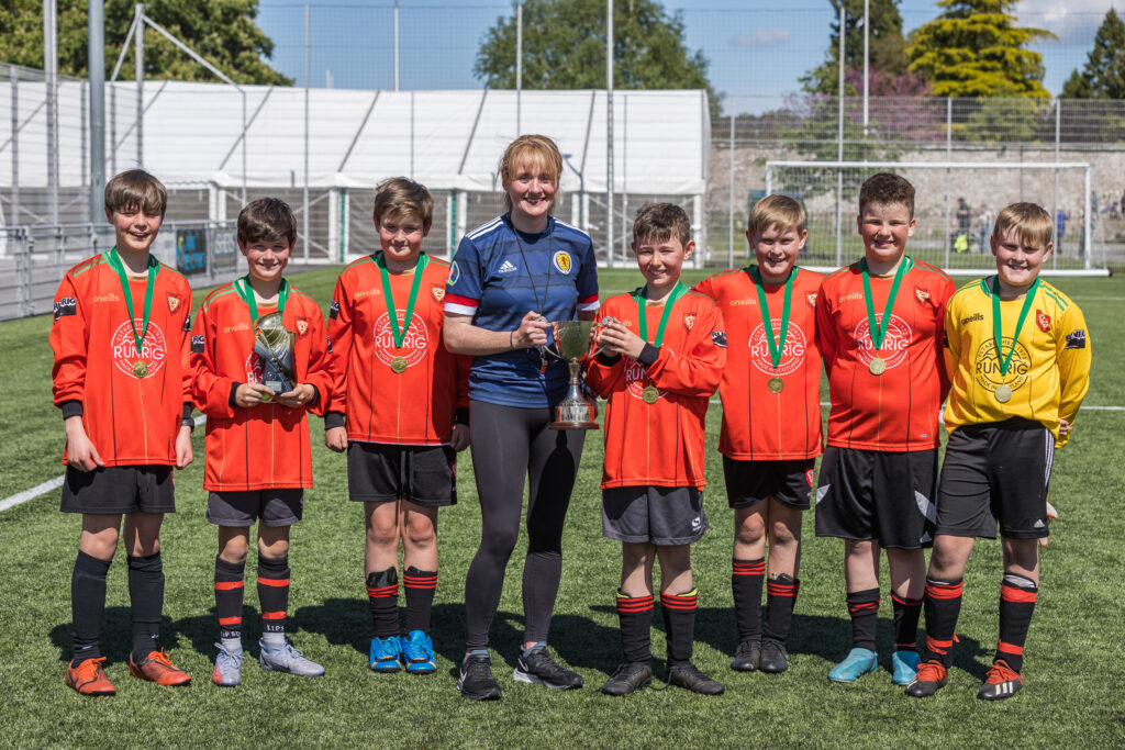 The winning team from Bun-sgoil Ghàidhlig Phort Rìgh being presented with the trophy and medals by Marina Murray, Development Director at Comunn na Gàidhlig, at Cuach na Cloinne, in Inverness. NO-F24-Bun-sgoil-Phort-Righ-2