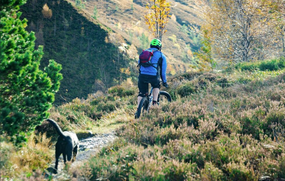 man cycling through hills in Scotland. 7 Autumn cycle routes in Scotland.