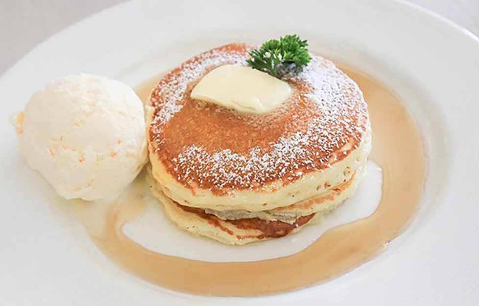 whisky pancake recipe. Image shows a stack of buttered pancakes in whisky sauce with a serving of ice cream on the side.