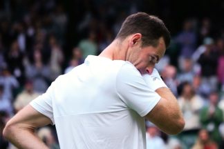 Andy Murray crying on Centre Court during his send off at the Wimbledon Tennis Championships, 2024. He is wearing a white tennis outfit and we are looking at his shoulders but we can see the side profile of his face as he wipes away his tears.