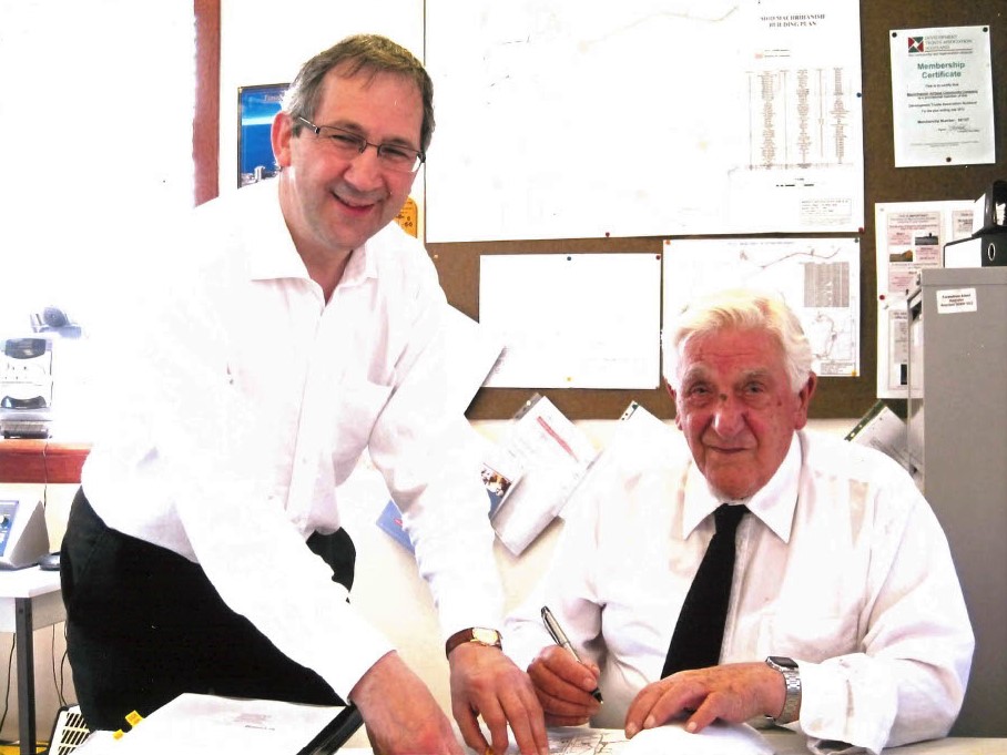 MACC director Don Mitchell, sitting, and Mark Ewing of TC Young Solicitors signing the paperwork transferring the site into community ownership in 2012.