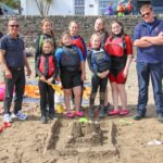 Dalintober Beach Group chairman Jamie MacLean, left, and sandcastle judge Stuart Newlands of HM Coastguard, right, with the winning team and their creation.