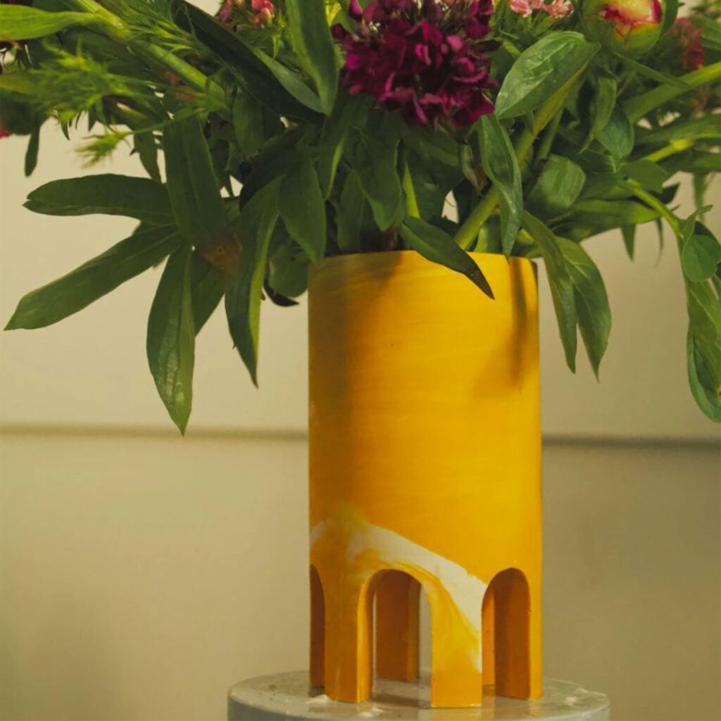 yellow cylindrical vase with open arches around base