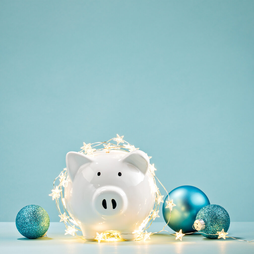White piggy bank draped with star shaped fairylights, blue baubles around