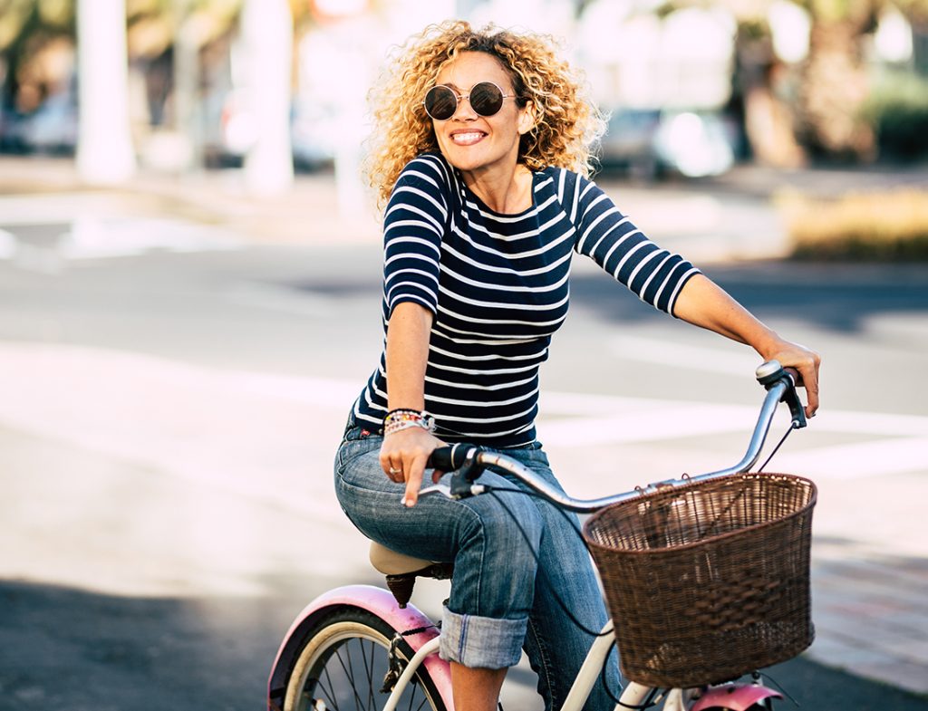 A lady on a bike, wearing sunglasses on a sunny day