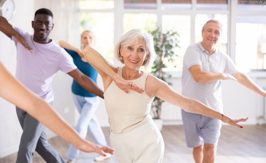 A mature lady enjoying a dance class of mixed ages