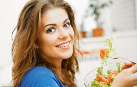 A young woman happily eating a salad