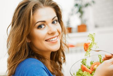 A young woman happily eating a salad