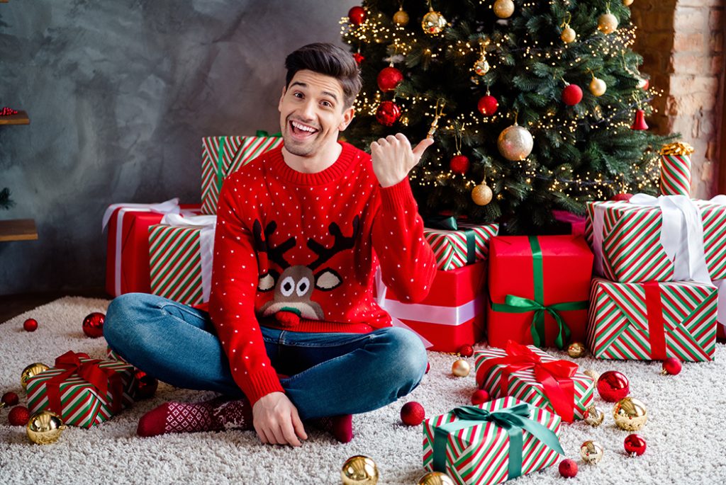 Man in Christmas jumper at Christmas tree Pic: Shutterstock