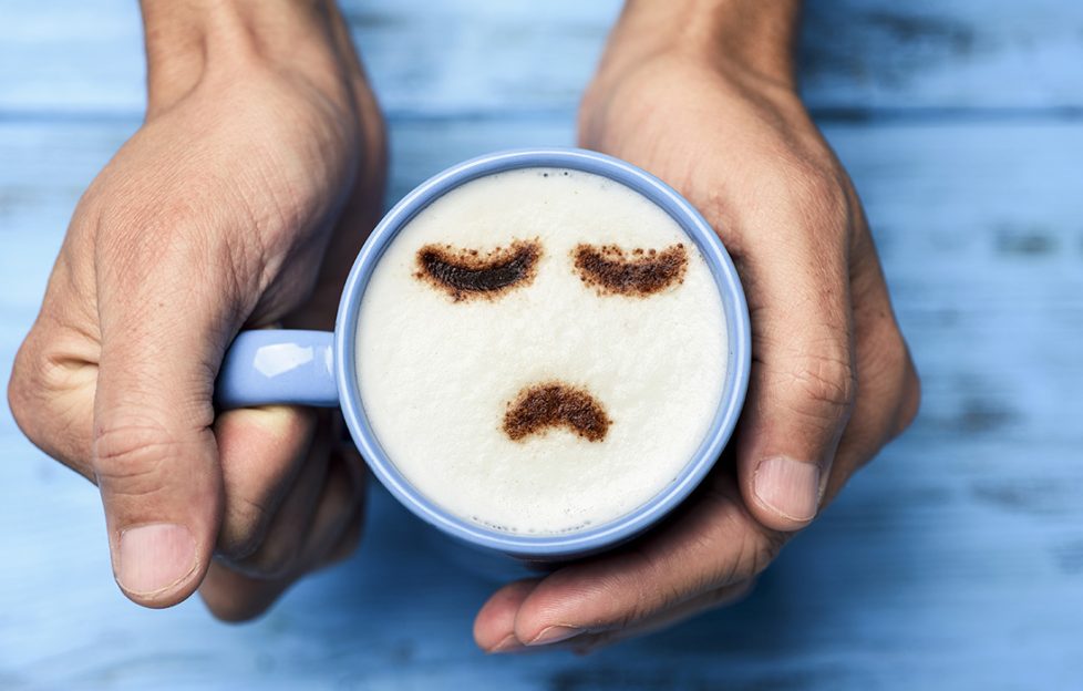 Blue mug with frothy coffee and a sad face sprinkled in cocoa powder Pic: Shutterstock