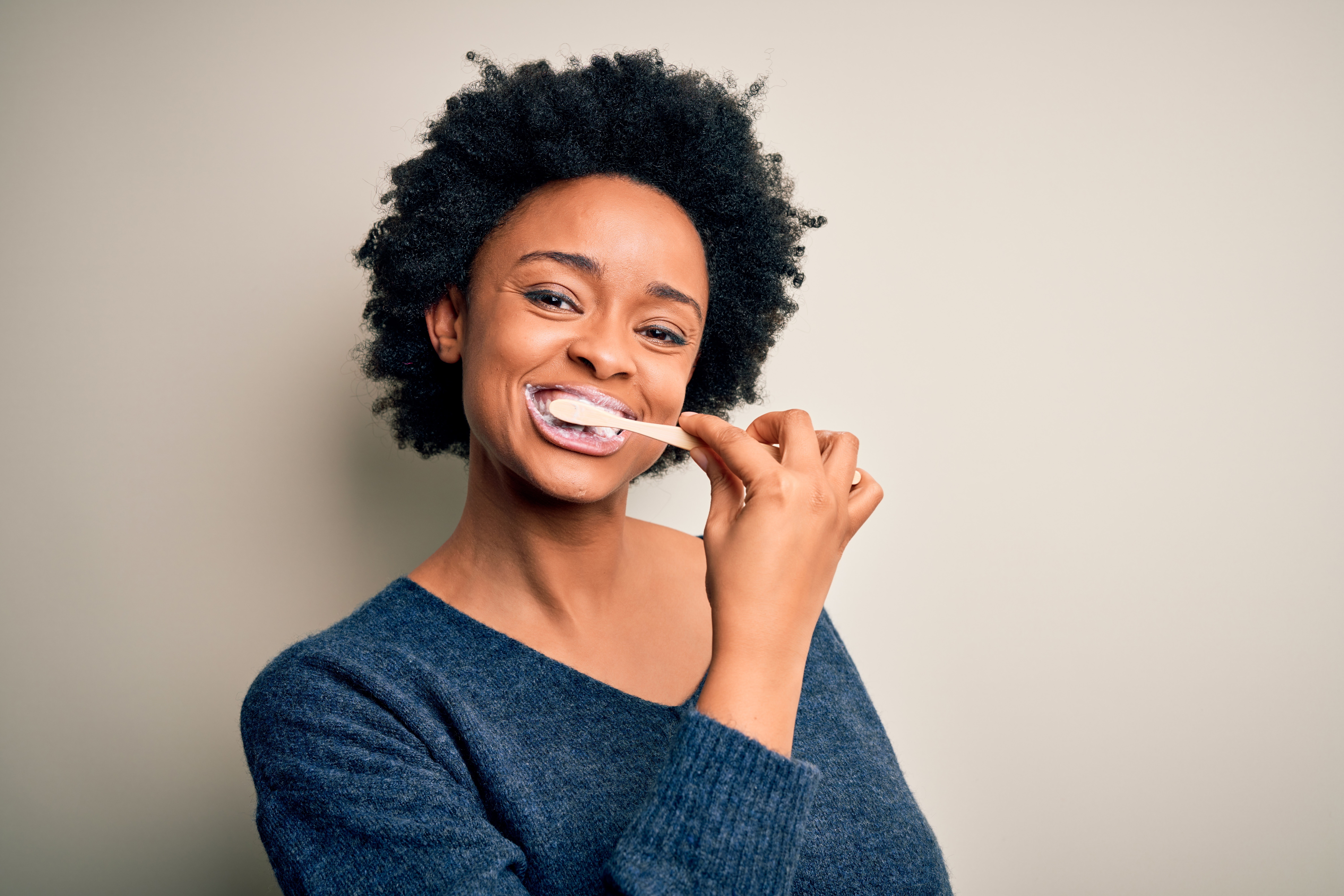 African american woman brushing her teeth using tooth brush and oral paste, cleaning teeth and tongue as healthy health care morning routine; 