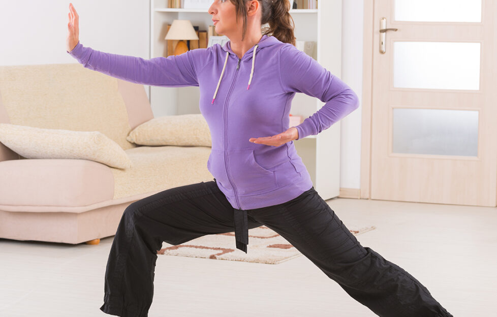 Beautiful woman doing qi gong tai chi exercise at home;