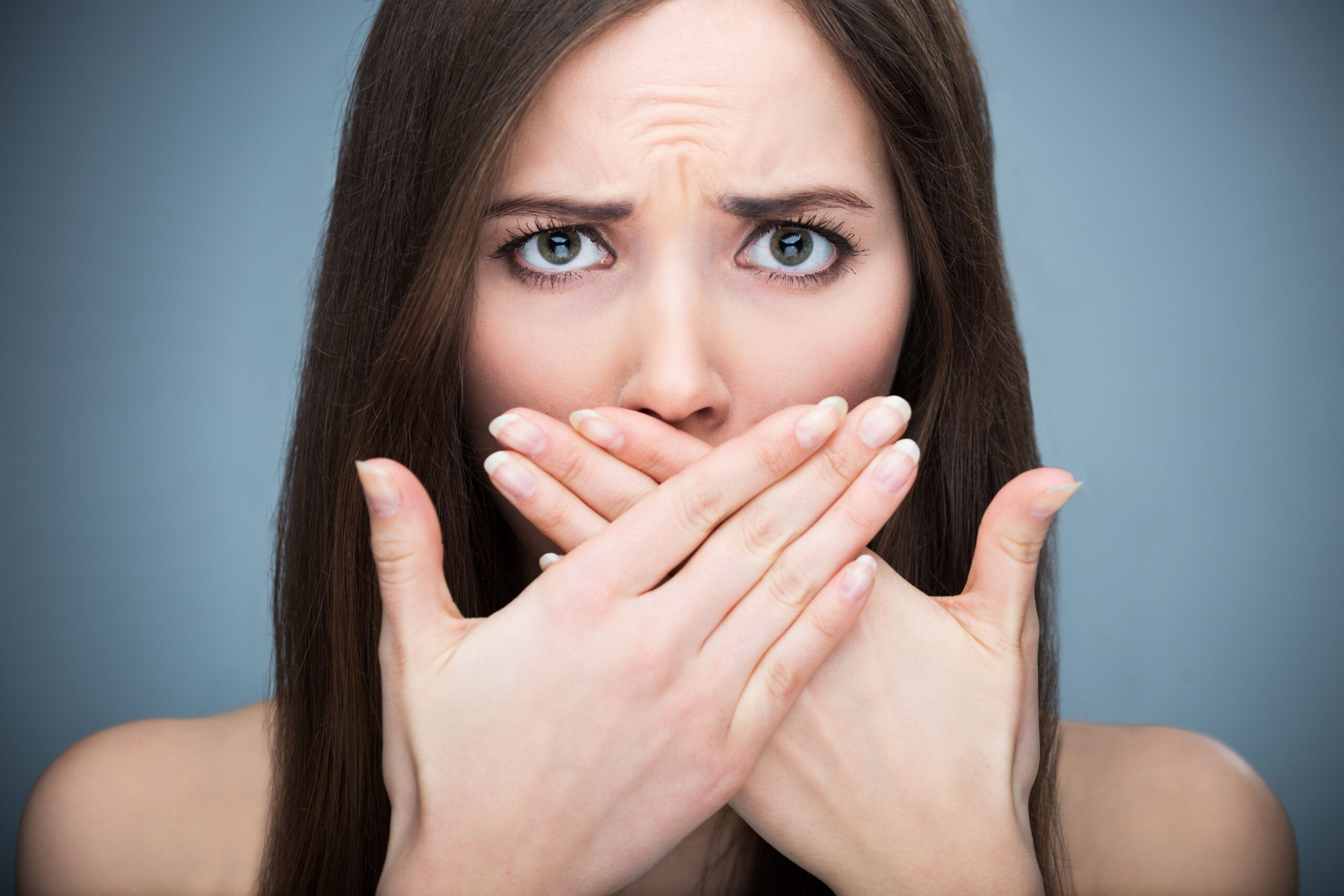 Brunette woman covering her mouth with both hands