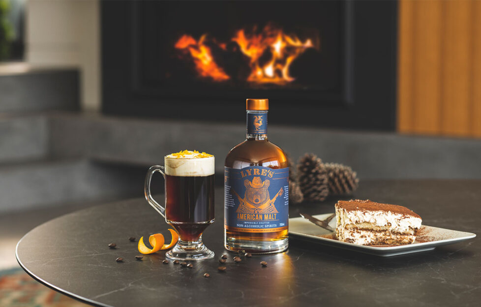 Roaring fire, classy room, grey marble table with slice of tiramisu, liqueur coffee, orange peel and bottle of Lyres American malt spirit