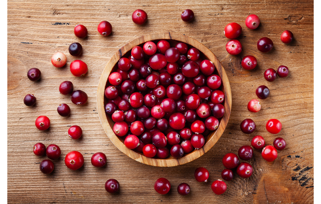 Cranberries in a wooden bowl on a wooden countertop