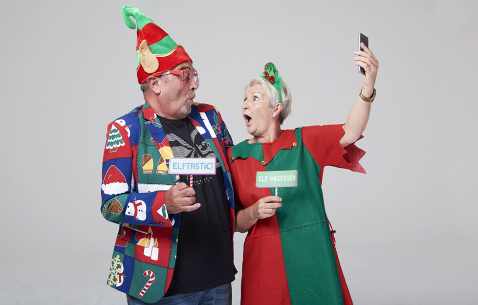 Mature couple in silly costumes for Elf Day, taking a selfie